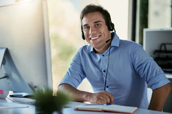 Hij staat klaar om je oproep aan te nemen. Portret van een medewerker van een callcenter die in een kantoor werkt. — Stockfoto