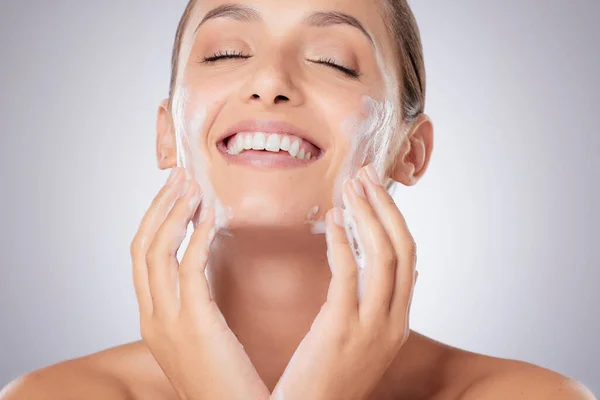 Dale a tu piel una buena limpieza. Fotografía de una joven hermosa lavándose la cara sobre un fondo gris. —  Fotos de Stock