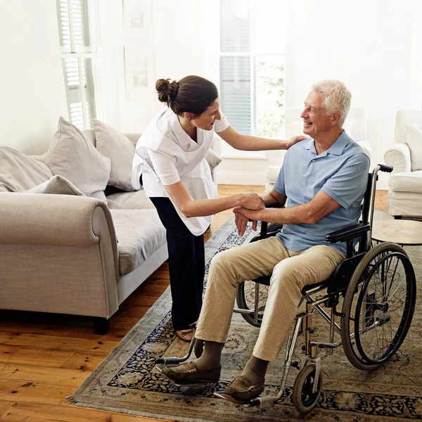 Догляд за літніми людьми це її покликання. Постріл доглядача, який допомагає старшому чоловікові в інвалідному візку вдома . — стокове фото