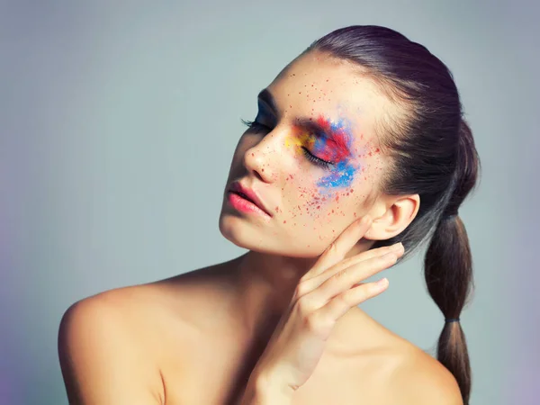 Makeup meets art. Studio shot of an attractive young woman with brightly colored makeup against a gray background. — ストック写真