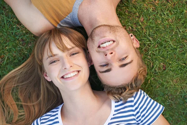 Relaxing in the park. Portrait of a happy young couple lying in the park. — ストック写真