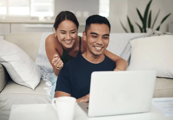 Encontraram algo interessante online. Tiro de um jovem casal usando um laptop juntos em casa. — Fotografia de Stock