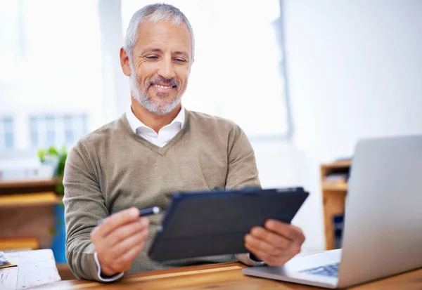 Este número de meses es excelente. Un hombre de negocios feliz usando una tableta en su escritorio en el trabajo. —  Fotos de Stock