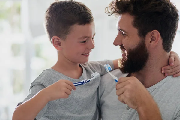 Tengo que mantener la caries a raya. Un disparo de un padre y su hijo pequeño cepillándose los dientes juntos en el baño en casa. — Foto de Stock