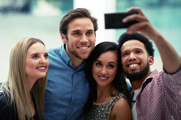 Este va directo a las redes sociales. Fotografía de un feliz grupo de amigos tomando una selfie con un smartphone en un club nocturno. — Foto de Stock