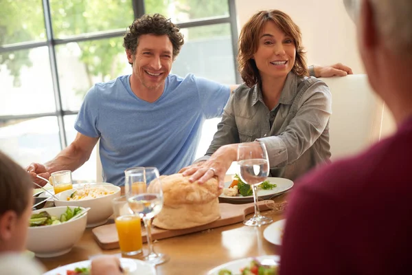 Eten en familie zijn de beste paren. Shot van een glimlachend paar die een maaltijd met hun familie. — Stockfoto