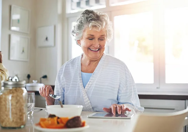 Щасливий вдома. Обрізаний знімок старшої жінки за допомогою цифрового планшета під час сніданку вдома . — стокове фото