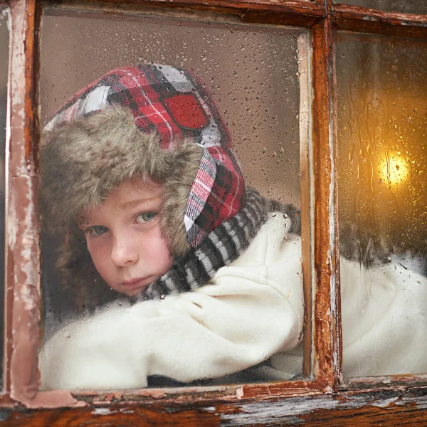 Regniga dagar utan något att göra... En ung pojke som ligger vid fönstret och ser uttråkad ut medan det regnar utanför. — Stockfoto