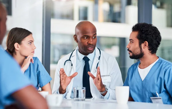 Insieme salvano delle vite. Girato di un gruppo di giovani medici concentrati che discutono insieme mentre sono seduti in ospedale. — Foto Stock