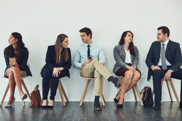 Connecting with the competition. Studio shot of a group of businesspeople talking while waiting in line. — Stock Photo, Image