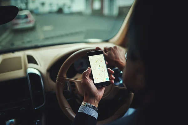 Dotarcie tam bezpiecznie dzięki GPS. Przycięte ujęcie biznesmena używającego telefonu GPS podczas jazdy samochodem. — Zdjęcie stockowe