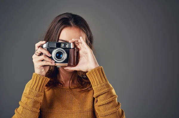 Sorri. Retrato de uma jovem atraente tirando fotografias contra um fundo cinza. — Fotografia de Stock