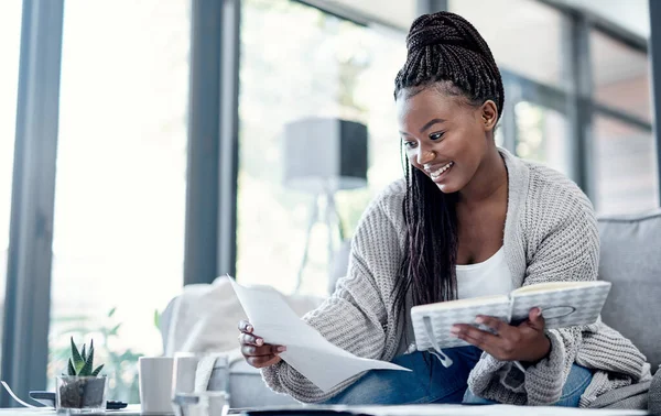 Je kunt geen prijs stellen op financiële vrijheid. Een foto van een jonge vrouw die het papierwerk thuis op de bank bekijkt.. — Stockfoto