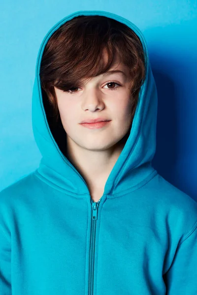 Ledig och självsäker. Porträtt av en ung pojke i blå huvtröja i ateljén. — Stockfoto