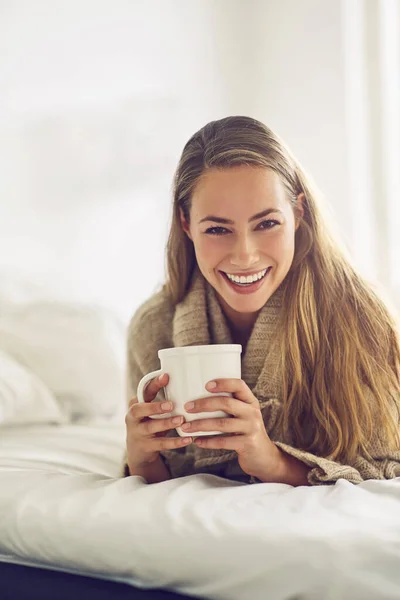 Start each day with a cup of positivity. Portrait of a young woman enjoying a warm beverage at home. — ストック写真