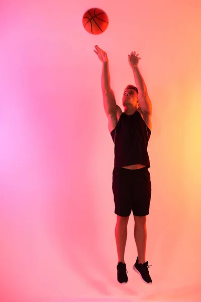 Стреляй. Студийный снимок красивого молодого баскетболиста, прыгающего на разноцветном фоне. — стоковое фото