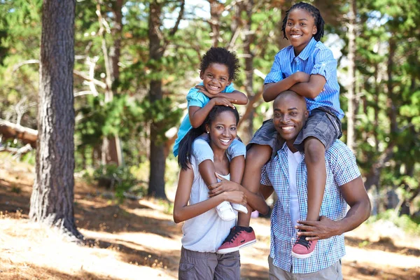 Se till att de inte blir för trötta. Porträtt av en mor och far som bär sina barn på axlarna medan de är ute och vandrar. — Stockfoto