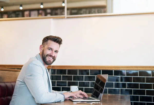 Es un gran lugar para hacer un poco de trabajo. Retrato recortado de un hombre de negocios moderno usando su computadora portátil en una cafetería. — Foto de Stock
