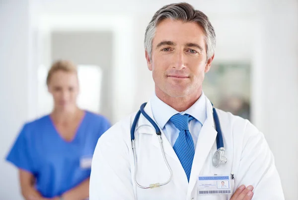 Du kommst zuerst. Porträt eines männlichen Arztes mit einem Kollegen im Hintergrund. — Stockfoto