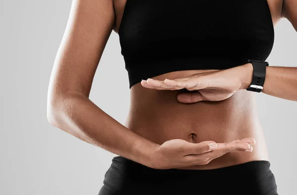 Sticking to a balanced diet. Cropped shot of an unrecognizable woman holding her hands against her stomach. — Stock Photo, Image