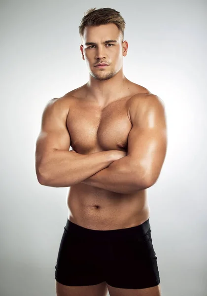 Algunas personas quieren promedio, deseo grande. Retrato de estudio de un joven musculoso posando con los brazos cruzados sobre un fondo gris. —  Fotos de Stock