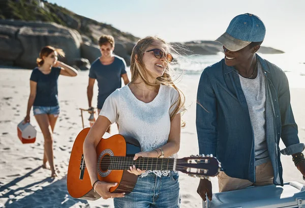 Theyll be jamming to the sounds of the sea. Shot of a group of young friends walking on the beach on a sunny day. — Stock Photo, Image