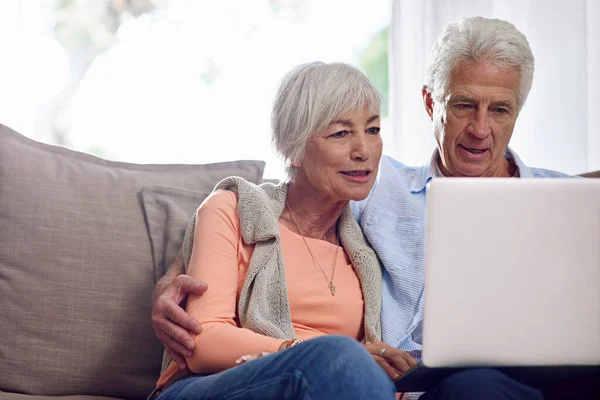 Gastando un poco de boo en línea. Fotografía de una pareja de ancianos usando un portátil en casa. —  Fotos de Stock