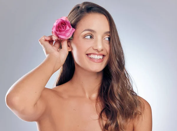 Ruusun kauneuden ruumiillistuma. Laukaus viehättävä nuori nainen seisoo yksin studiossa ja poseeraa ruusu hiuksissaan. — kuvapankkivalokuva