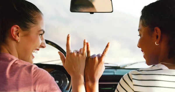 A diversão começa agora. Tiro cortado de duas jovens mulheres atraentes colocando as mãos juntas para fazer um sinal em um veículo. — Fotografia de Stock