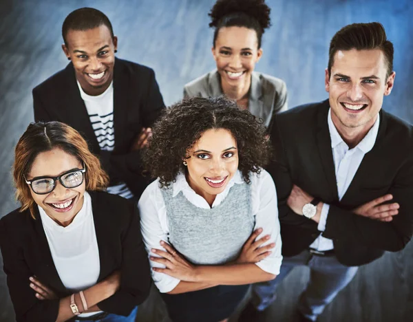 De coördinatie van onze inspanningen maakt ons een geweldig team. Hoge hoek opname van een groep zakenmensen die samen staan in een kantoor. — Stockfoto