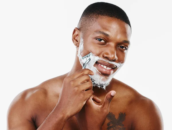 Non usa e getta come la mia lama. Studio ritratto di un bel giovane uomo radersi i peli del viso con un rasoio su uno sfondo bianco. — Foto Stock