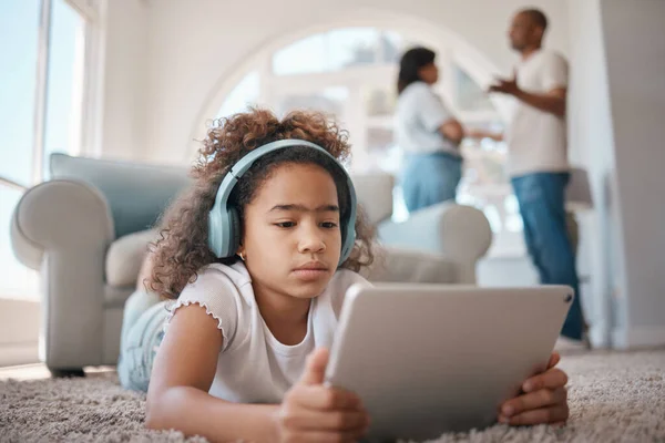 Le cose stanno andando male. Girato di una giovane ragazza che usa un tablet digitale mentre i suoi genitori discutono. — Foto Stock