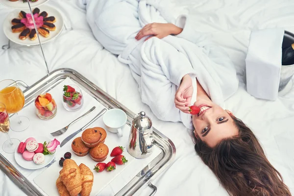 Je prends un peu de repos pour me gâter. Tourné d'une jolie jeune femme profitant d'un petit déjeuner luxueux dans sa chambre. — Photo