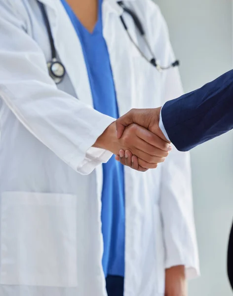 与可信赖的伙伴一起改造医疗服务。医生在医院与商人握手的剪影. — 图库照片