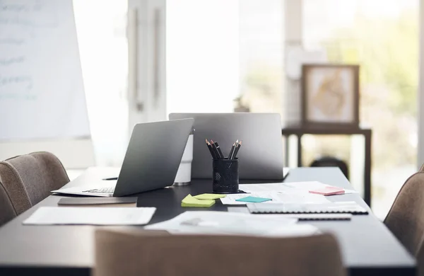 Grandes planos são feitos aqui. Tiro de natureza morta de computadores portáteis e papelada em uma mesa em um escritório moderno. — Fotografia de Stock