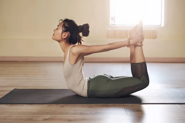 Strek al je spanningen weg. Full length shot van een aantrekkelijke jonge vrouw stretching en uit te werken in een yoga studio. — Stockfoto