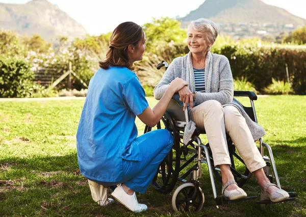我想你需要一些新鲜空气。拍到一个年轻的女护士和一个坐在轮椅上的老年病人在外面. — 图库照片
