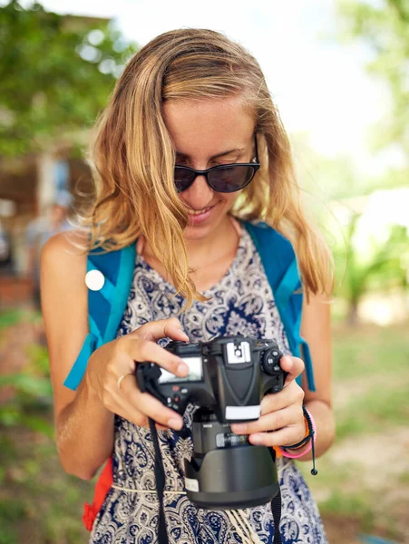 É difícil escolher o melhor. Tiro de uma jovem mulher feliz olhando para fotografias em sua câmera durante as férias. — Fotografia de Stock