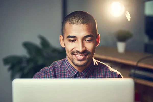 Trabajando hasta tarde pero trabajando duro. Recorte de un joven diseñador trabajando hasta tarde en un ordenador portátil en una oficina. — Foto de Stock