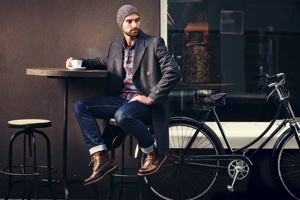 Kawa to zawsze dobry pomysł. Strzał przystojnego młodzieńca w zimowym ubraniu pijącego napój w kawiarni przy chodniku. — Zdjęcie stockowe
