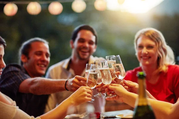 Los buenos tiempos son para celebrar con amigos. Tiro de un grupo de jóvenes amigos felices brindando con champán en una cena en el patio trasero. — Foto de Stock