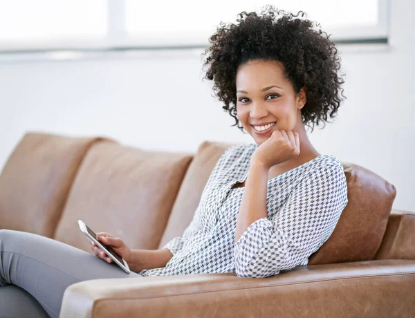 Abwickeln zu Hause mit meinem Tablet. Porträt einer attraktiven Frau, die mit ihrem Smartphone auf dem Sofa sitzt. — Stockfoto