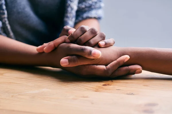 Apoyando a un amigo. La foto recortada de dos personas cogidas de la mano cómodamente en una mesa. — Foto de Stock