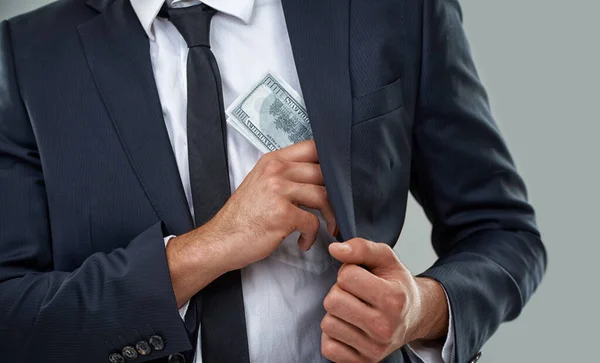 Die wahren Verbrecher tragen Anzüge, keine Sturmhauben.... Ausschnittbild eines Geschäftsmannes, der Geld in die Tasche steckt. — Stockfoto