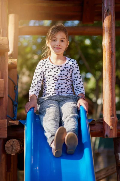 The slide is my favourite at the park. Portrait of a little girl playing on a slide at the park. — ストック写真