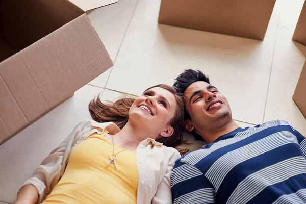 A novos começos.... Tiro de um jovem casal deitado no chão enquanto faz uma pausa de se mudar para uma nova casa. — Fotografia de Stock