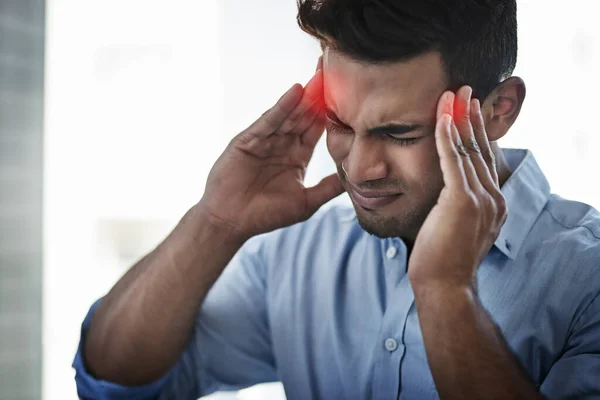 This pain is so intense. Shot of a young businessman suffering with a headache at work. — Stock Photo, Image