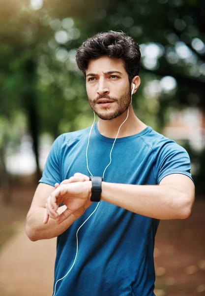 Puedo hacer el tiempo. Fotografía de un joven deportivo escuchando música mientras hace ejercicio al aire libre. — Foto de Stock