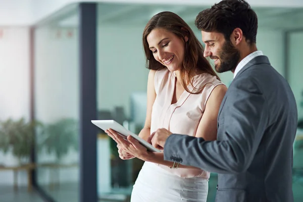 Positiviteit inspireert productiviteit. Foto van een jonge zakenman en zakenvrouw die samen een digitale tablet gebruiken in een kantoor. — Stockfoto