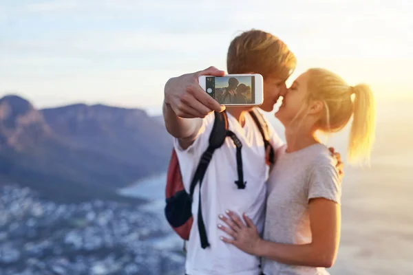 Catturare il loro bacio. Colpo ritagliato di una giovane coppia che si fa un selfie durante un'escursione. — Foto Stock